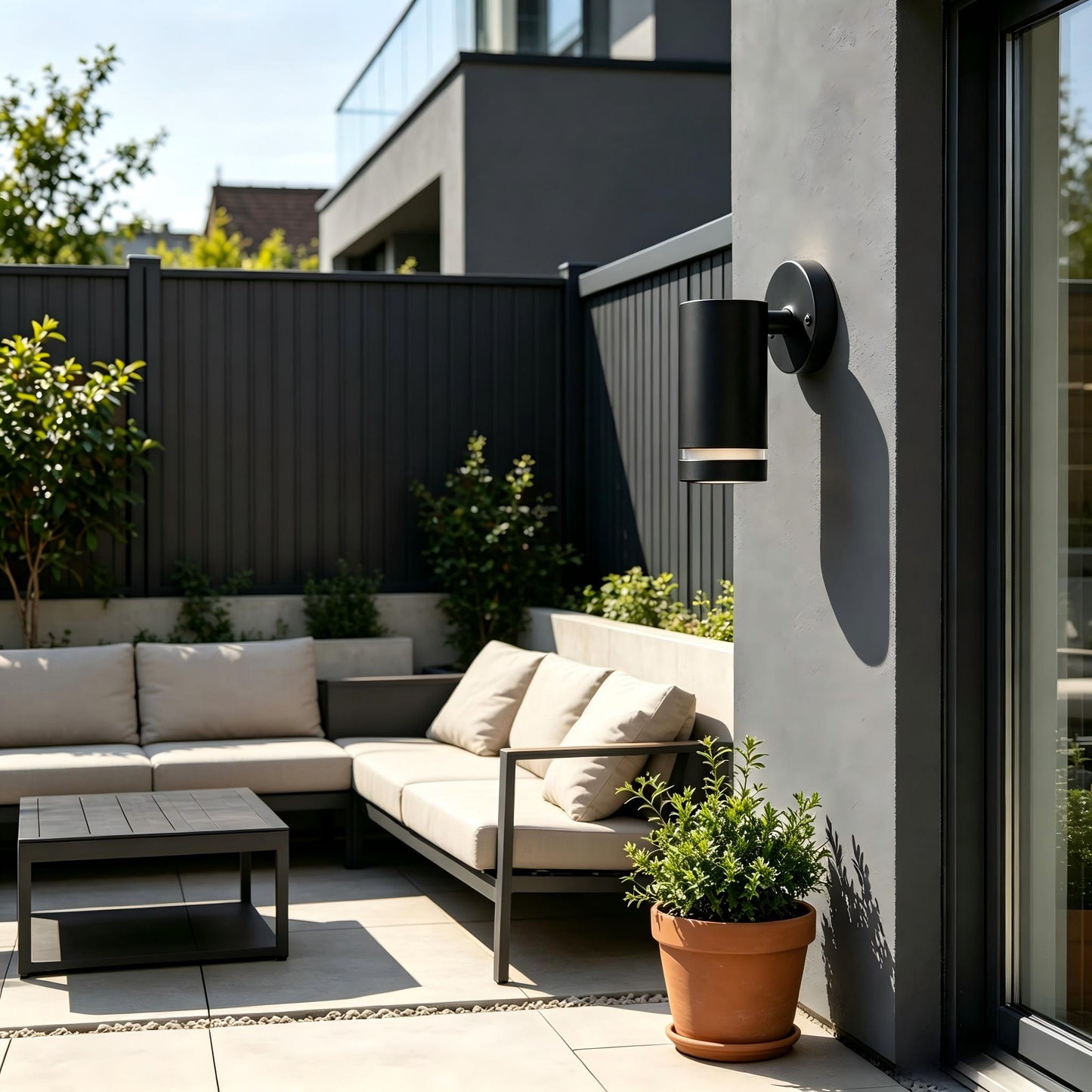 Matte black cylinder outdoor wall light close shot unlit on dark stone exterior wall