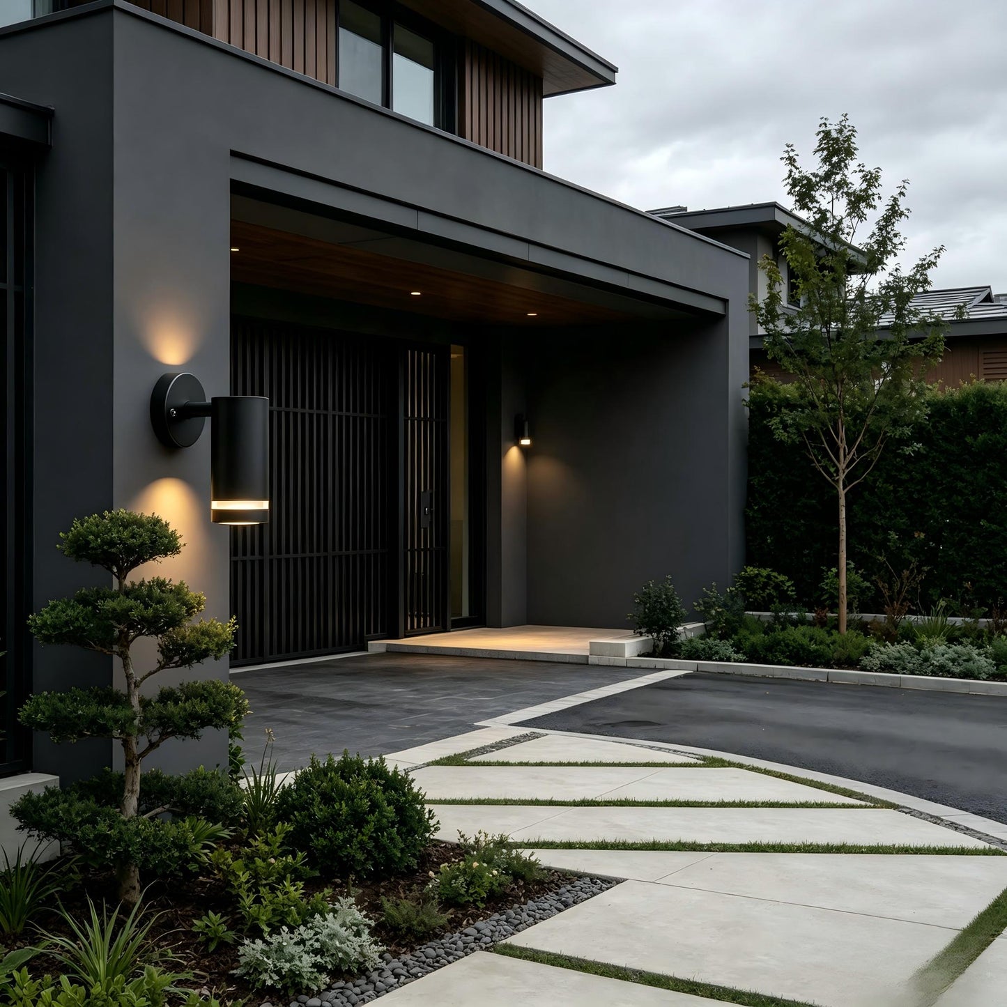 Dark metal outdoor wall light lit up beside garden plants backyard patio