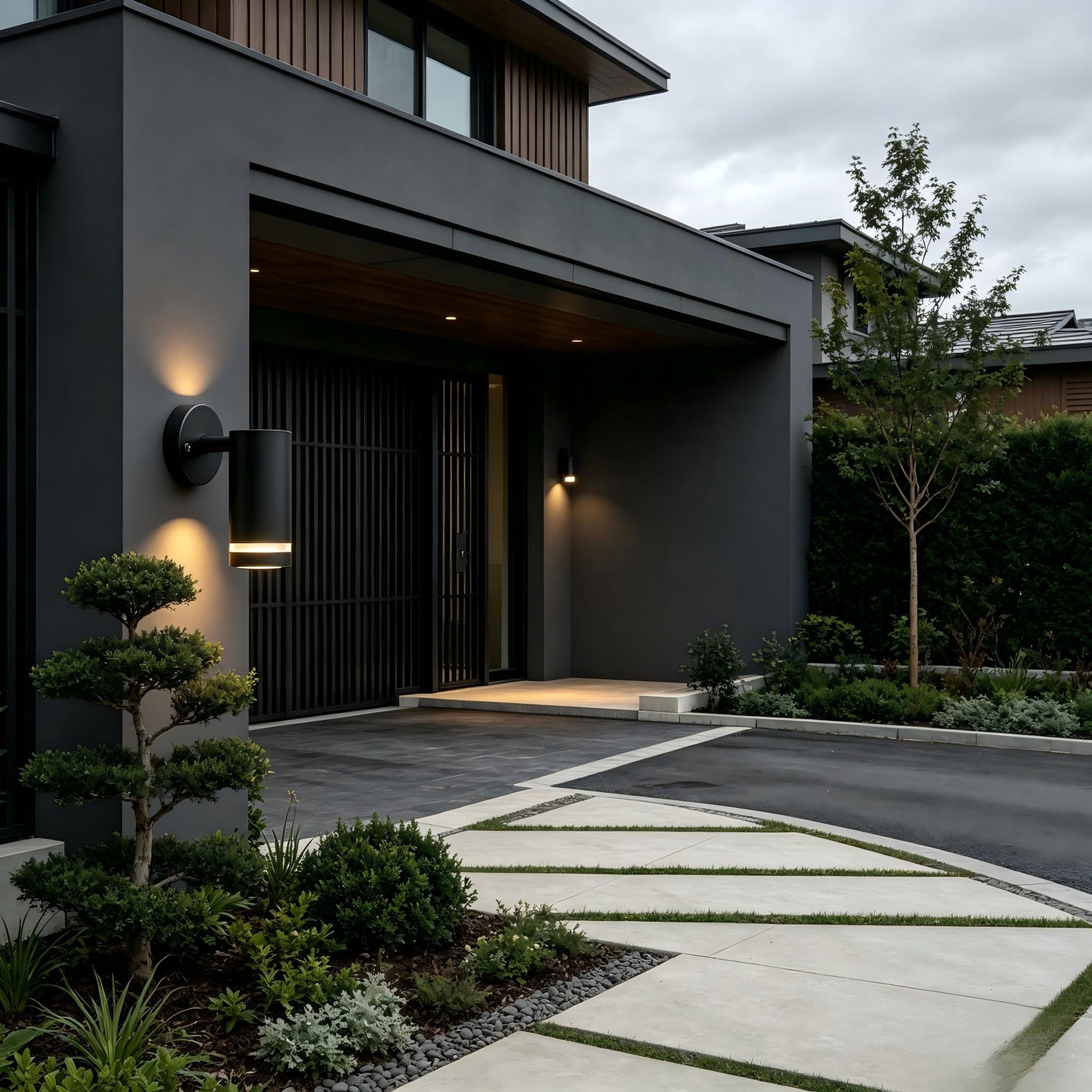 Dark metal outdoor wall light lit up beside garden plants backyard patio