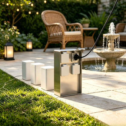 Stainless steel outdoor power box on a stone patio near a garden water fountain.