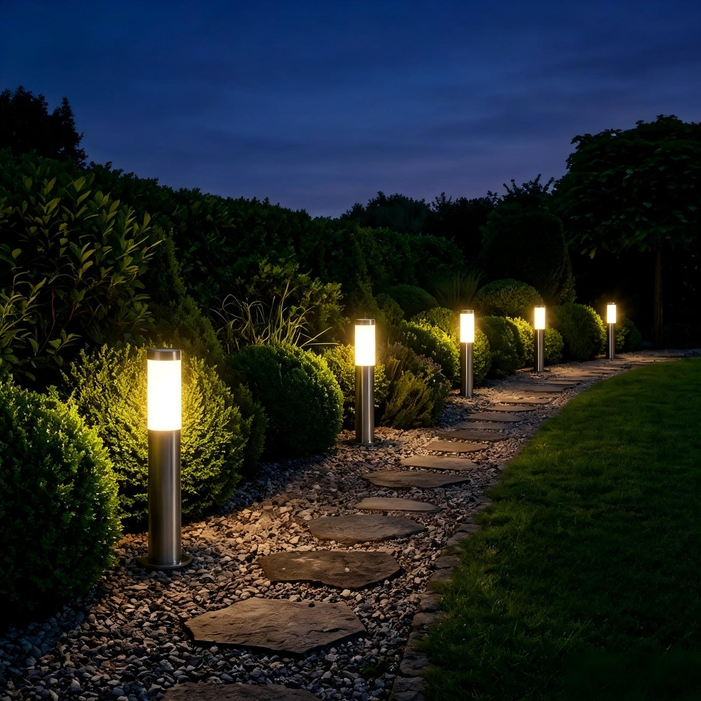 Stainless steel bollard lights creating warm pathway lighting in a landscaped garden.