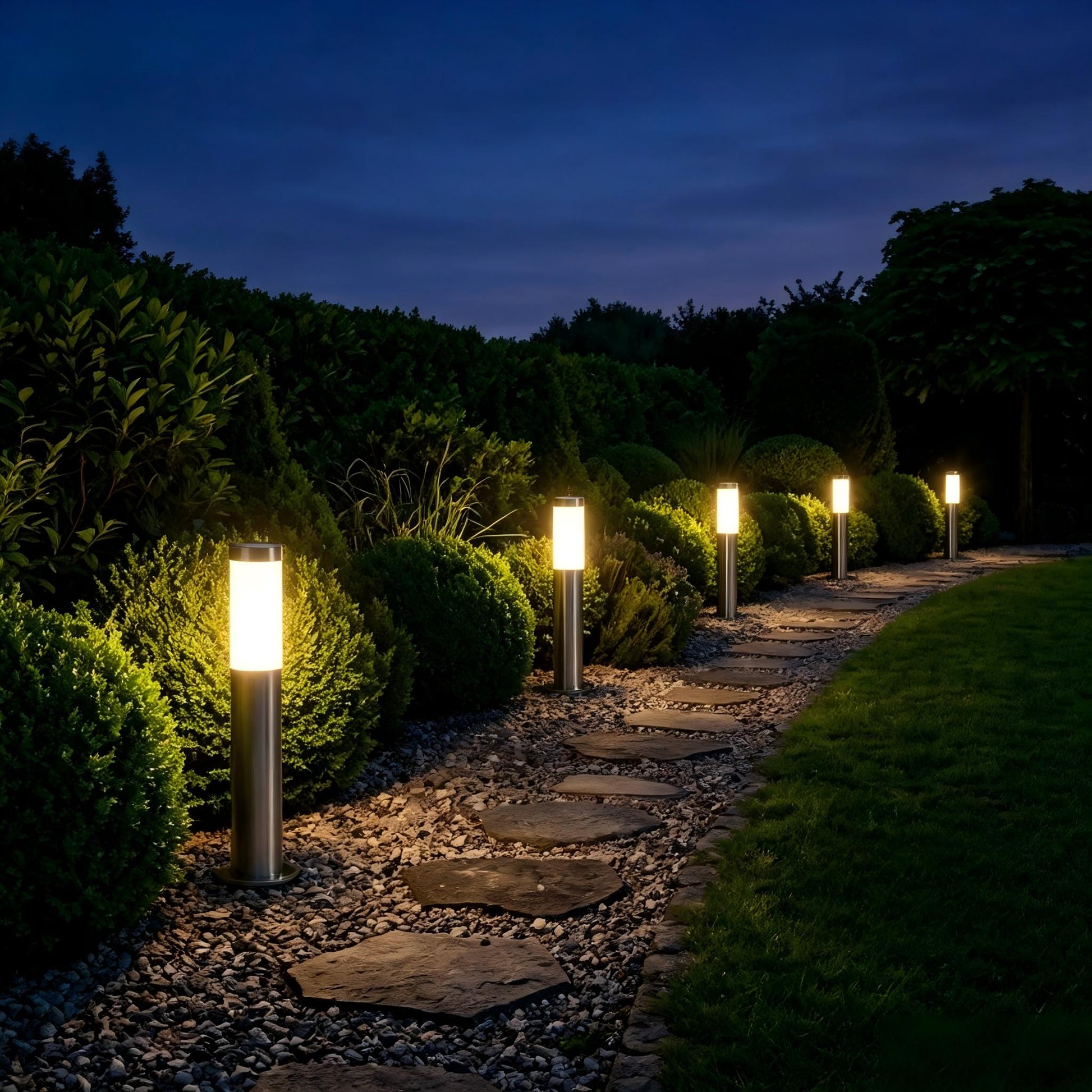 Stainless steel bollard lights creating warm pathway lighting in a landscaped garden.